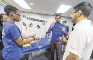  ??  ?? Teens Jared Brown (left), Dhruvesh Patel and Rafael Montez explain their nanoscienc­e project to guests during the finale of GSU’s STEM camp for deaf students. BILL BANKS FOR THE AJC