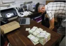  ?? JAE C. HONG — THE ASSOCIATED PRESS ?? In this photo, bundles of $20 bills are placed on a table as Jerred Kiloh, owner of the Higher Path medical marijuana dispensary, prepares a trip to Los Angeles City Hall to pay his monthly tax payment in cash in Los Angeles. For Kiloh, the cash is a...