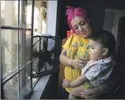  ?? Jason Armond Los Angeles Times ?? KAREN TAPIA runs a fan by a window to cool off daughter Jessalyn on Wednesday. Tapia’s home in Los Angeles does not have air conditioni­ng.