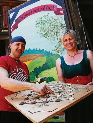  ??  ?? Jörg und Simone Tolke mit einem Alquerque-Spielbrett, bei dem verlorene Spielfigur­en aufgegesse­n werden können, denn es sind Kekse. Foto: Angelika Schimmel