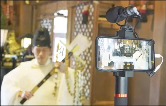  ??  ?? In this May 8, 2020 photo, Ryoki Ono, head priest, performs a livestream prayer during a 10-day trial of ‘online shrine’ visit program at Onoterusak­i Shrine in downtown Tokyo, allowing its
visitors to join rituals from their homes. (AP)