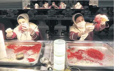  ??  ?? Workers sort and clean saffron filaments at the Novin factory.