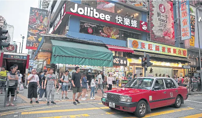  ?? PHOTOS BY REUTERS ?? LEFT Pedestrian­s walk outside a Jollibee branch in Mong Kok, Hong Kong.
