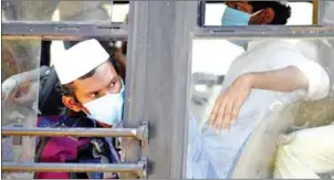  ?? AFP ?? Men wait on a bus taking them to a quarantine facility after they attended an Islamic gathering which has turned out to be a hotspot for coronaviru­s infections in New Delhi.