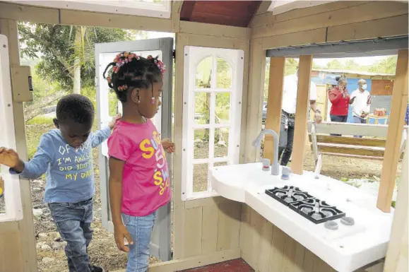  ??  ?? Four-year-old Kelecia Gayle and her brother Majeed-selvin examine this play house that was built for her, alongside a brand-new onebedroom house for their family by First Union Financial Limited. Both structures were presented to the family yesterday at West Prospect, St Catherine.