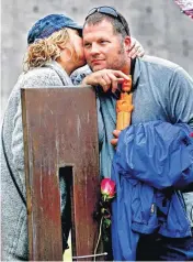  ??  ?? Mickey Paul Maroney, son of bombing victim Mickey B. Maroney, is consoled Tuesday by his girlfriend, Christi Jacob, at his father’s chair at the memorial after the 21st anniversar­y remembranc­e ceremony.