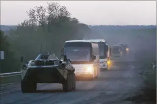  ?? / Associated Press ?? A tank accompanie­s buses with Ukrainian servicemen to the penal colony in Olyonivka after they left besieged Mariupol’s Azovstal steel plant, in territory under the government of the Donetsk People’s Republic in eastern Ukraine on Friday.