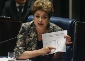  ?? MARIO TAMA, GETTY IMAGES ?? Suspended President Dilma Rousseff points to an economic chart displaying oil prices while answering a question from a senator on the Senate floor during her impeachmen­t trial on Monday in Brasilia, Brazil.