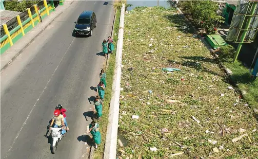  ?? BOY SLAMET/JAWA POS ?? BAU MENYENGAT: Murid-murid harus menutupi hidungnya saat melawati Sungai Mangetan Kanal, Gedangan, yang penuh dengan sampah. Meskipun sering dilakukan pengangkut­an, kiriman sampah seolah tidak pernah berhenti.