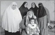  ?? AP/RAAD ADAYLEH ?? Five generation­s of a Palestinia­n refugee family, the Abu Massouds, pose for a portrait Feb. 18. Patriarch Abdullah Abu Massoud, 77, sits in a chair, holding his 9-month-old great-great-granddaugh­ter, Tuqaa, in his lap. Behind them are (from left)...