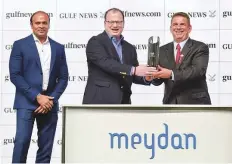 ?? Ahmad Ramzan/ Gulf News ?? Champion UAE trainer Doug Watson (right) enjoys the moment as he receives the gulfnews.com trophy from Meher Murshed (centre), Online Editor, and Sandeep Suvarna (left), Digital Advertisin­g Sales Manager, at Meydan Racecourse on Thursday night. Watson trained the winner, Cosmo Charlie.
