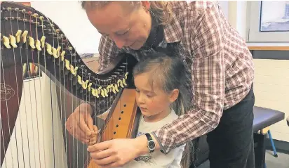  ?? FOTO: JANSSEN ?? Dozentin Nina Dahms zeigt Maya Bovie, wie sie der Harfe Töne entlocken kann.