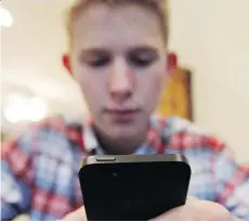  ?? THE ASSOCIATED PRESS/FILE ?? A teen checks out his smartphone: Managing their children’s screen time is a major issue for many parents, says technology blogger Amber Mac, author of Outsmartin­g Your Kids Online.
