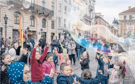  ?? MAURICIO LIMA/THE NEW YORK TIMES PHOTOS ?? A street artist entertains children with bubbles April 7, after the war started, in Lviv, Ukraine.