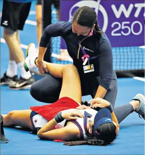  ?? ?? Tough day at the office: Emma Raducanu plays a forehand (left) and has treatment on a hip spasm (above) during her three-set defeat by Wang Xinyu (right) in Linz yesterday