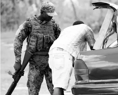  ?? FILE ?? A soldier conducts a search of a vehicle at a checkpoint in Whitehouse, Westmorela­nd, which is one of three parishes, including Hanover and St James, under a state of public emergency. The security measure restricts personal freedom and grants extraordin­ary powers to soldiers and the police.