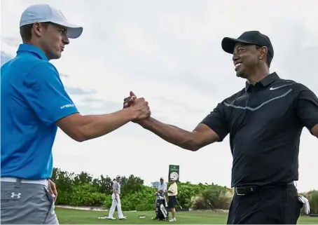  ?? — Reuters ?? Playing for my kids: Tiger Woods (right) shaking hands with Jordan Spieth on the driving range during Tuesday’s practice round of the Hero World Challenge in Bahamas.