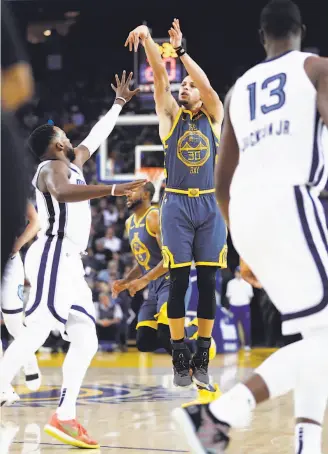  ?? Scott Strazzante / The Chronicle ?? The Warriors’ Stephen Curry scores his 15,000th career point on a three-pointer in the second quarter against the Grizzlies. Curry had 20 points in the victory.