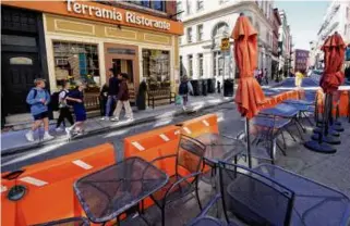  ?? CHARLES KRUPA/AP ?? People walked past tables at a dining area set up in parking spots outside Terramia Ristorante on May 10, 2022, in the North End.