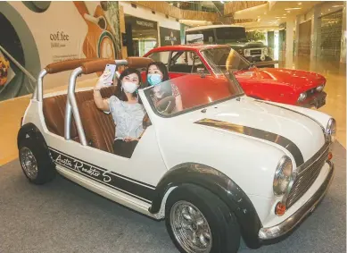  ?? RIANA SETIAWAN/JAWA POS ?? NIKMATI SUASANA: Aurellia Widjaja (kiri) dan Claudia Irawan berswafoto di salah satu mobil vintage di lantai ground Lenmarc Mall kemarin (26/2).