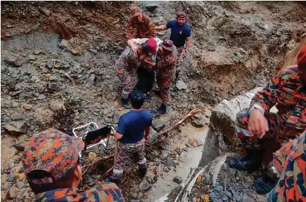  ?? (Foto ihsan JBPM) ?? Pasukan bomba membantu pesakit buah pinggang meredah laluan yang terputus akibat banjir dan tanah runtuh di Kampung Bawang, Tamparuli, semalam.