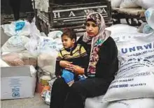  ?? AFP ?? A woman with a child waits to receive food supplies from the United Nations offices in the Khan Yunis refugee camp in the southern Gaza Strip.