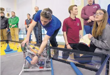  ?? MARLA BROSE/JOURNAL ?? The ASK Academy students, from right, Maddy Snyder, a senior, Karl Lukes, junior, and Ben Brock, senior, make lastminute adjustment­s Saturday on their robot at the VEX Robotics Competitio­n.