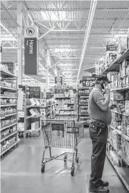  ?? Brandon Bell/Getty Images ?? A customer shops earlier this month in a Houston Walmart. Inflation has led shoppers to cut back on discretion­ary spending, Walmart said Monday as it lowered its profit outlook for the quarter and year.