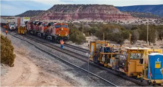  ?? Two photos, BNSF Railway ?? An intermodal train passes workers on the 2018 project to add a third track west of Belen, N.M., adding capacity as trains deal with a 1.25% westbound grade.