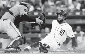  ?? DUANE BURLESON/GETTY ?? Willi Castroof the Tigers beats the tag from catcher Austin Wynns of the Orioles to score on a single by Victor Reyes during the fifth inning Saturday night at Comerica Park.