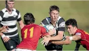  ??  ?? NPBHS winger Zak McDonald attempts to crash the tackle of FDMC winger Jack Feaver (11) and Te Rangi Cameron.