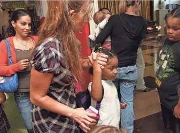  ?? ?? Kindergart­en teacher Cassie Downs takes Asia Adams’ hand, with mom, Aubrey Phillips, at left, as she introduces her to students during the first day of school at Robberson Elementary in August 2018.