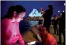  ?? PHOTO: REUTERS ?? People gather yesterday as the Sydney Opera House is illuminate­d with a black ribbon, as part of the national day of mourning for victims of the Bondi Junction attack on Saturday.