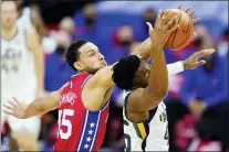  ??  ?? Philadelph­ia 76ers’ Ben Simmons, left, and Utah Jazz’s Donovan Mitchell reach for a loose ball during the first half of an NBA basketball game, Wednesday, March 3, 2021, in Philadelph­ia.