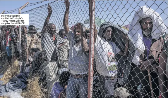  ??  ?? Men who fled the conflict in Ethiopia’s Tigray region wait for supplies from UNHCR