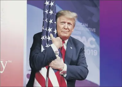  ??  ?? STARRY-EYED: President Donald Trump hugs the American flag as he arrives to speak at Conservati­ve Political Action Conference.