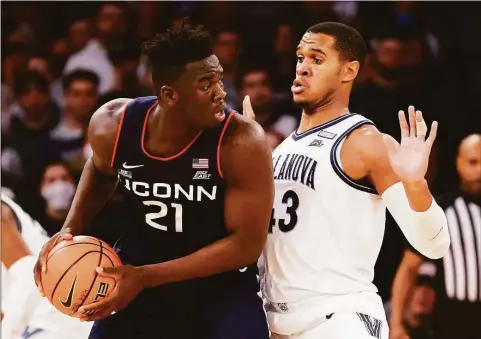  ?? Tim Nwachukwu / Getty Images ?? UConn’s Adama Sanogo, left, looks to pass against Villanova’s Eric Dixon during the 2022 Big East Tournament at Madison Square Garden.