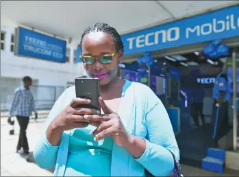  ?? XINHUA ?? A woman uses a mobile handset produced by Shenzhen-based Transsion Holdings Ltd in Nairobi, Kenya.