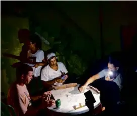  ?? RAMON ESPINOSA/ASSOCIATED PRESS ?? People played dominoes by flashlight in Havana Wednesday. Hurricane Ian knocked out Cuba’s power grid.