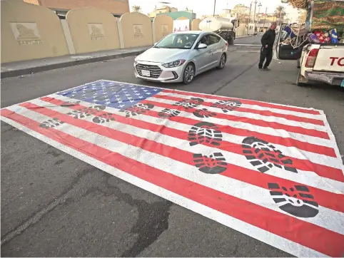  ?? Picture: AFP ?? TRAMPLED. A mock US flag is laid on the ground for cars to drive on in the Iraqi capital of Baghdad yesterday, following news of the killing of top Iranian Quds Force commander Qasem Soleimani in a US strike on his convoy at Baghdad internatio­nal airport.