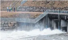  ?? FOTO: DPA ?? Passanten bestaunen am 6. Januar bei Wolterding­en den Abfluss des Regenrückh­altebecken­s.