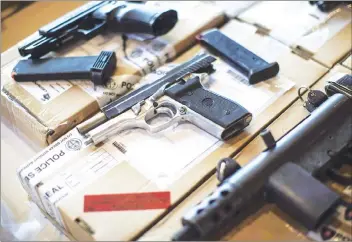  ?? CP PHOTO ?? Police display guns seized during a series of raids at a press conference in Toronto in 2013. Federal NDP Leader Jagmeet Singh is formally asking the prime minister to immediatel­y give cities the leeway to ban handguns.
