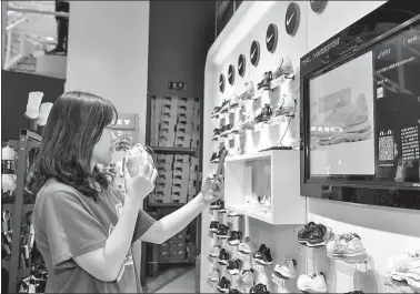  ?? PROVIDED TO CHINA DAILY ?? A consumer picks up a shoe and accesses relevant product informatio­n and buyer reviews from an “intelligen­t wall” at an Intersport­Tmall store in Beijing.