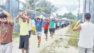  ?? — AFP photo ?? Refugees at the Australian detention centre on Manus Island in Papua New Guinea. PNG officials deployed police vehicles and buses around a shuttered Australian refugee camp as a deadline passed for some 400 detainees to move from the controvers­ial...