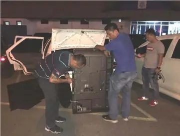  ??  ?? Police personnel unload one of the three television­s from the suspects’ car.