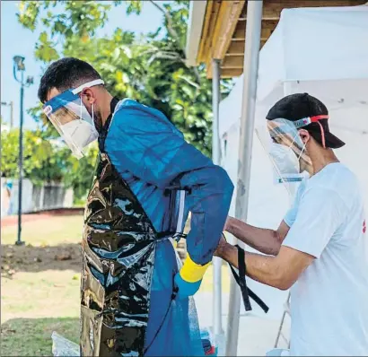  ?? RICARDO ARDUENGO / AFP ?? Personal sanitario se pone los equipos para atender a enfermos de coronaviru­s en Loiza (Puerto Rico)