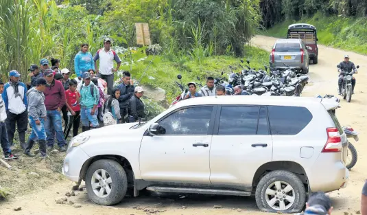  ?? AP ?? People gather around a car riddled by bullets on the road leading to Tacueyo, in southwest Colombia yesterday. Five indigenous leaders of the Tacueyo reservatio­n were killed late Tuesday when the two vehicles they were travelling in were ambushed by gunmen the government says are part of a dissident front of Revolution­ary Armed Forces of Colombia.