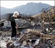  ?? AP/CHRIS PIZZELLO ?? Marsha Maus, a longtime resident of the Seminole Springs Mobile Home Park in Agoura Hills, Calif., looks through her charred belongings Sunday after wildfires destroyed her neighborho­od.