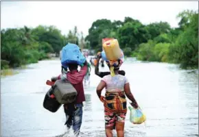  ?? AFP ?? People cross the flooded road to Monrovia airport after heavy rains on July 1.