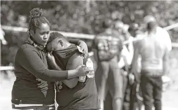  ?? Jason Fochtman / Houston Chronicle ?? Residents comfort one another after a shooting last month that left two men dead in the community of Tamina. Four people have been arrested in the deaths of Jaquise Williams, 23, and Akeem Russell, 24.